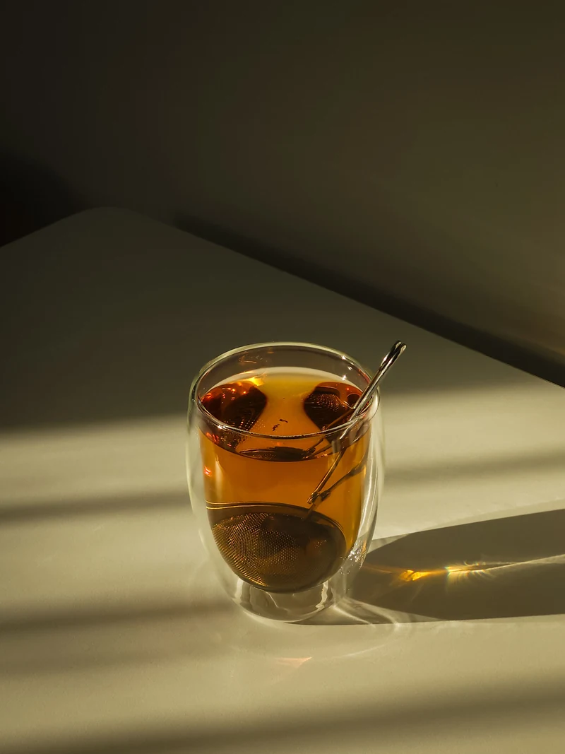 Una taza de té con luz cálida de la tarde y sombras suaves sobre la mesa